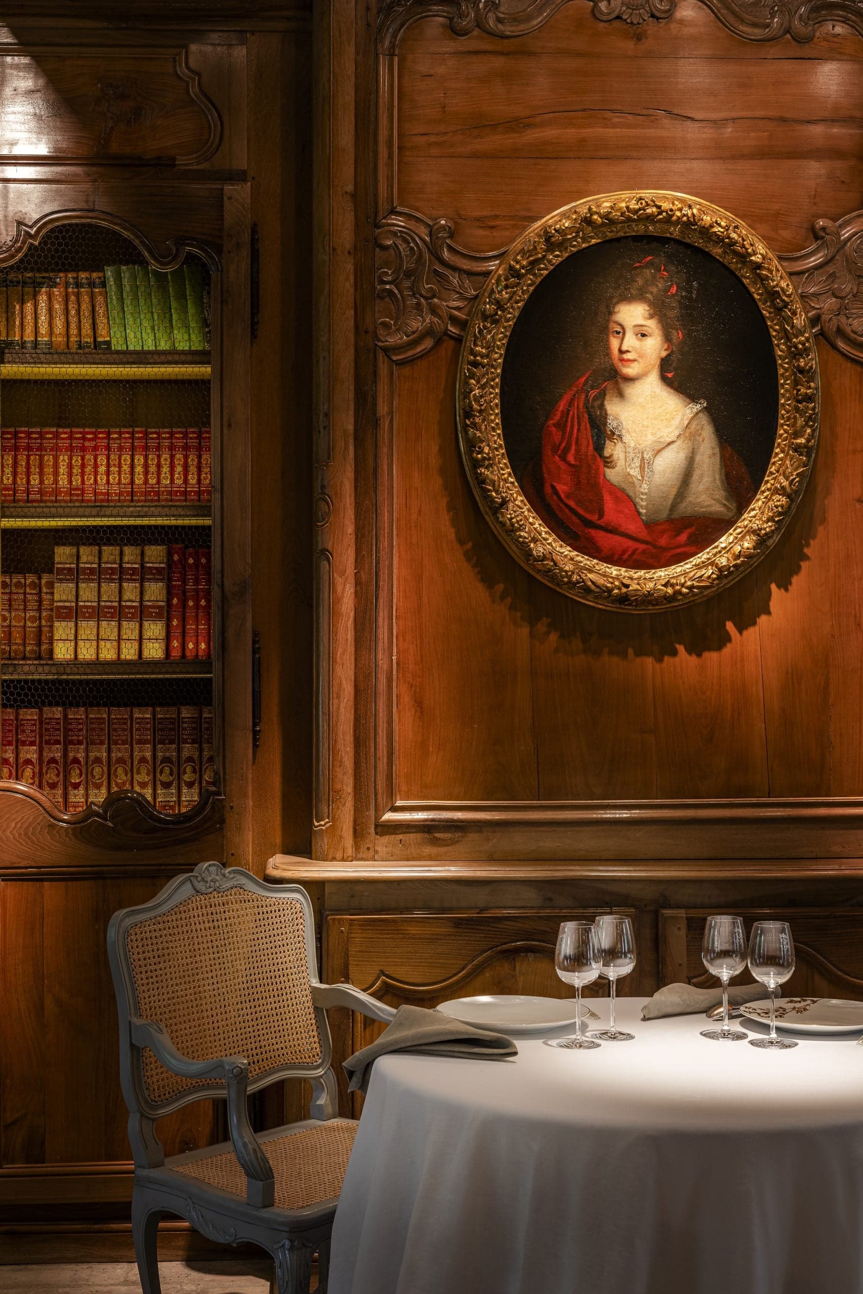 A table for two in a wood-panelled dining room, the Empress Eugénie watching from an oval frame.
