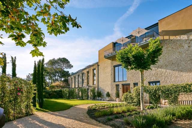 The villa from the garden path — a plane tree in leaf, terraces with parasols, lavender beneath the windows.