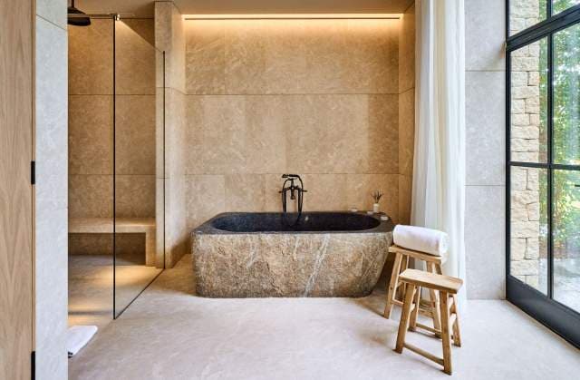 A stone bathtub set into limestone walls in a Villa La Coste suite bathroom.