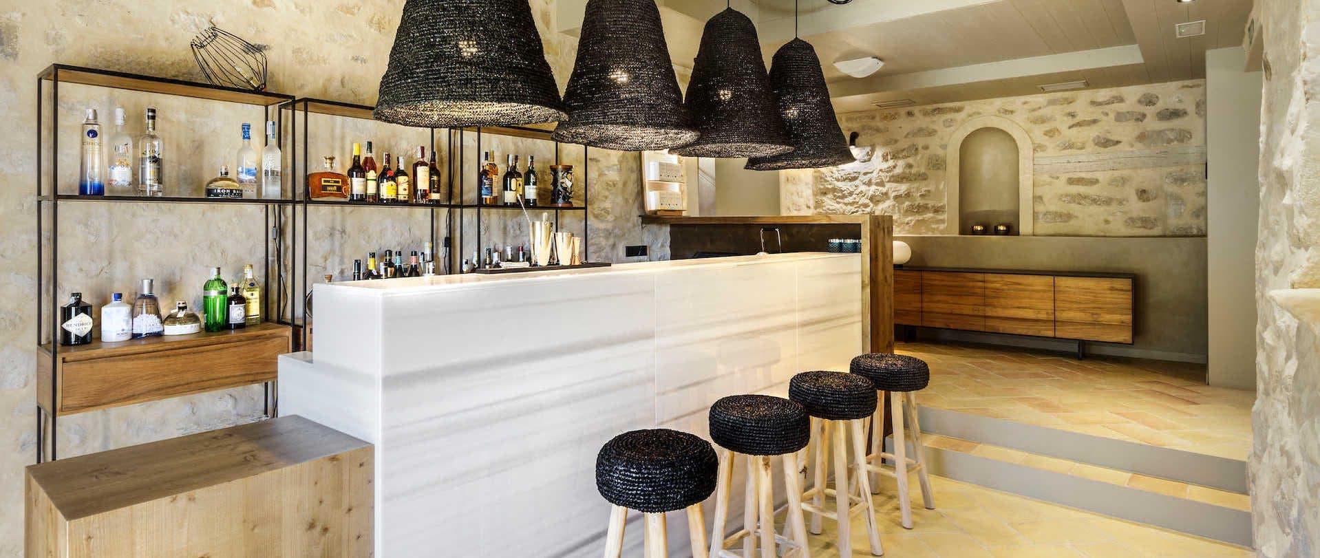 A panoramic view of the manor's bar, low light on polished wood and pale stone.