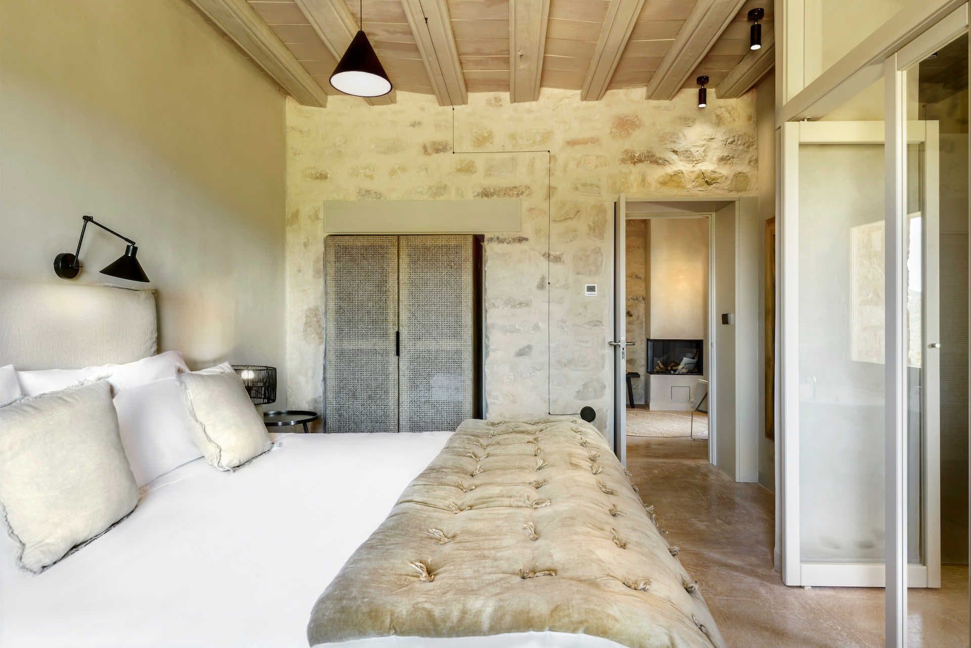 A junior suite at the manor, restored beams above pale linen and a wide window onto the Aragonese light.