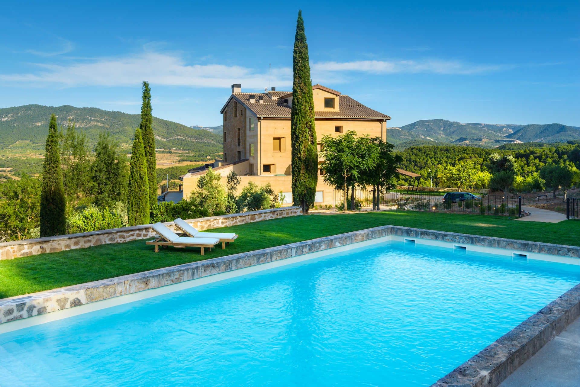 The pale Aragonese stone of Torre del Marqués reflected in the manor's pool at the height of the afternoon.