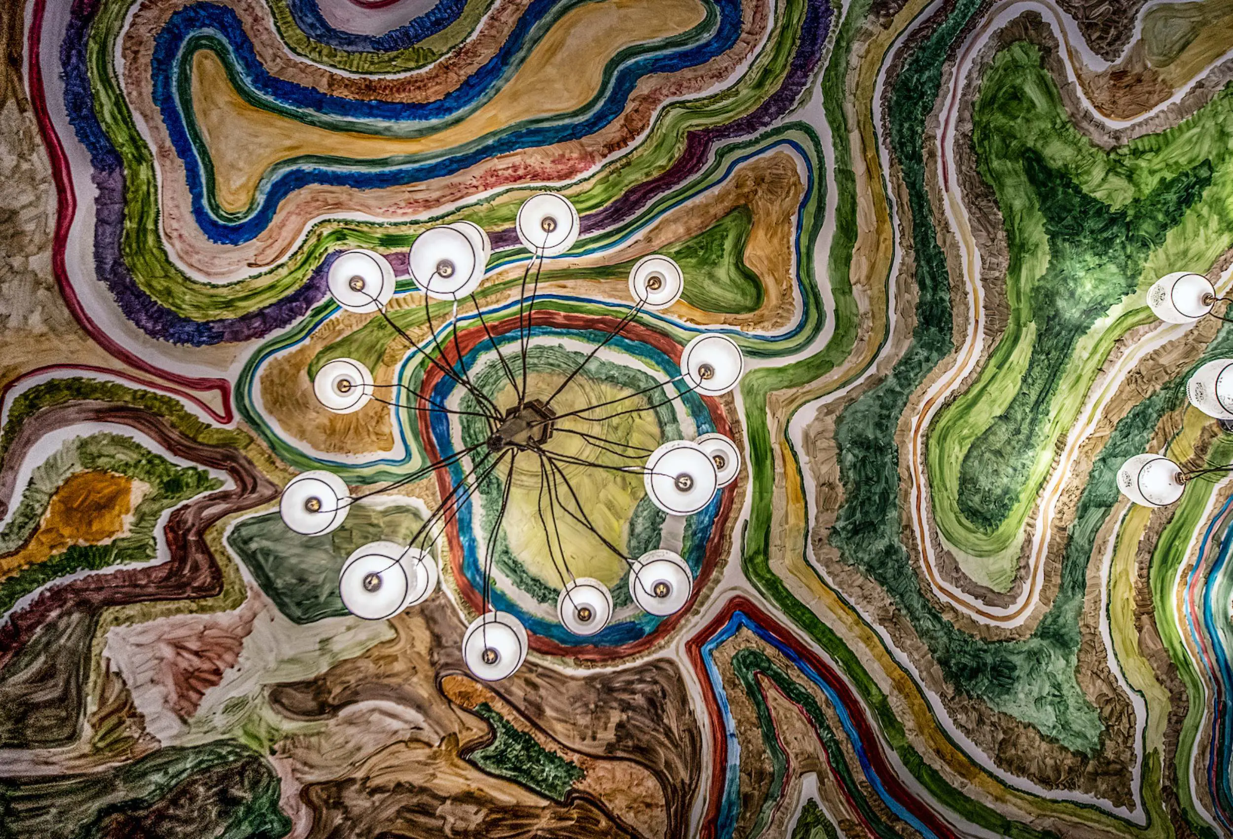 The drawing room ceiling at The Fife Arms, painted by Zhang Enli with rivers of colour curling around the central pendant lights.