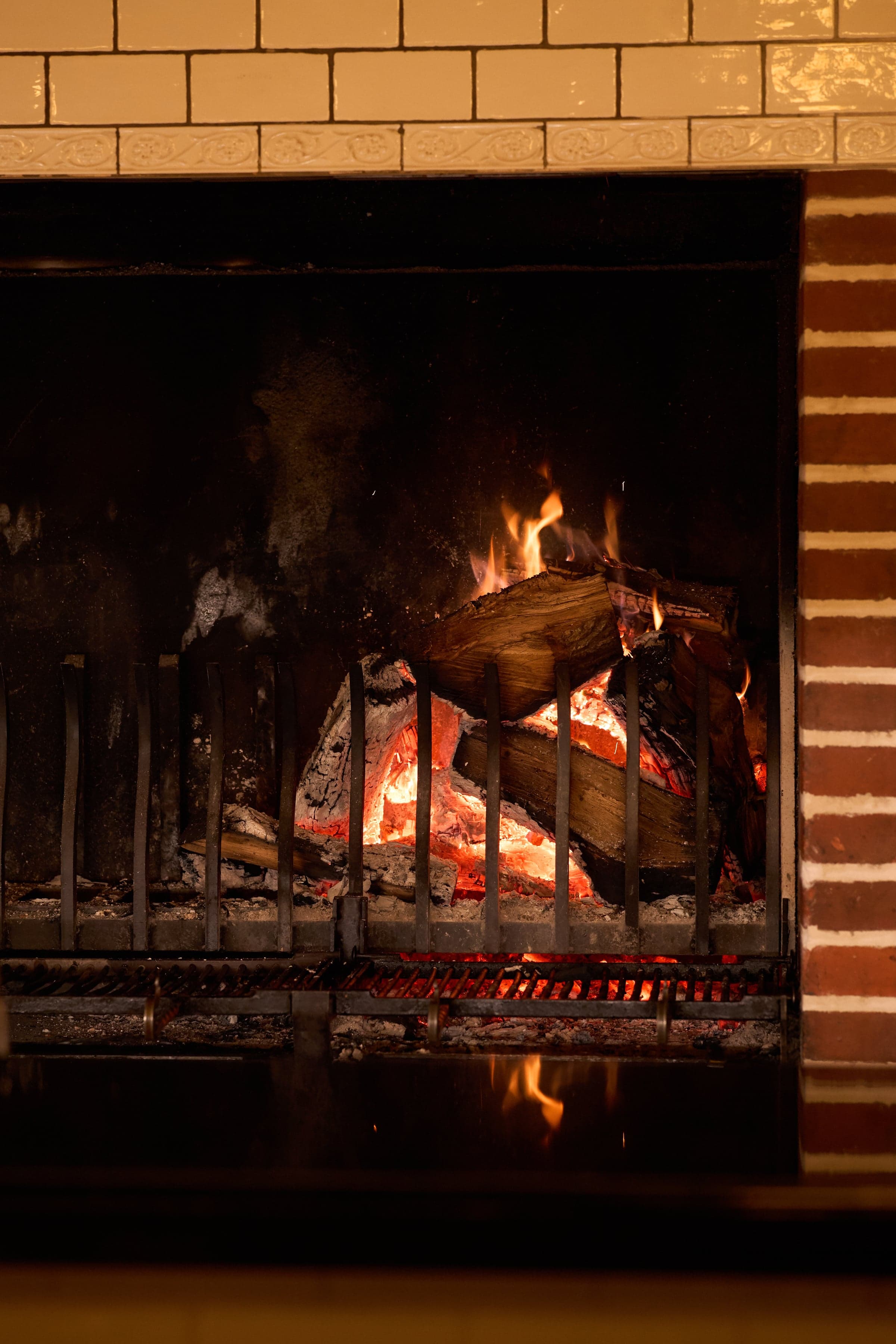 A stone fireplace lit at night, two armchairs angled toward the fire.