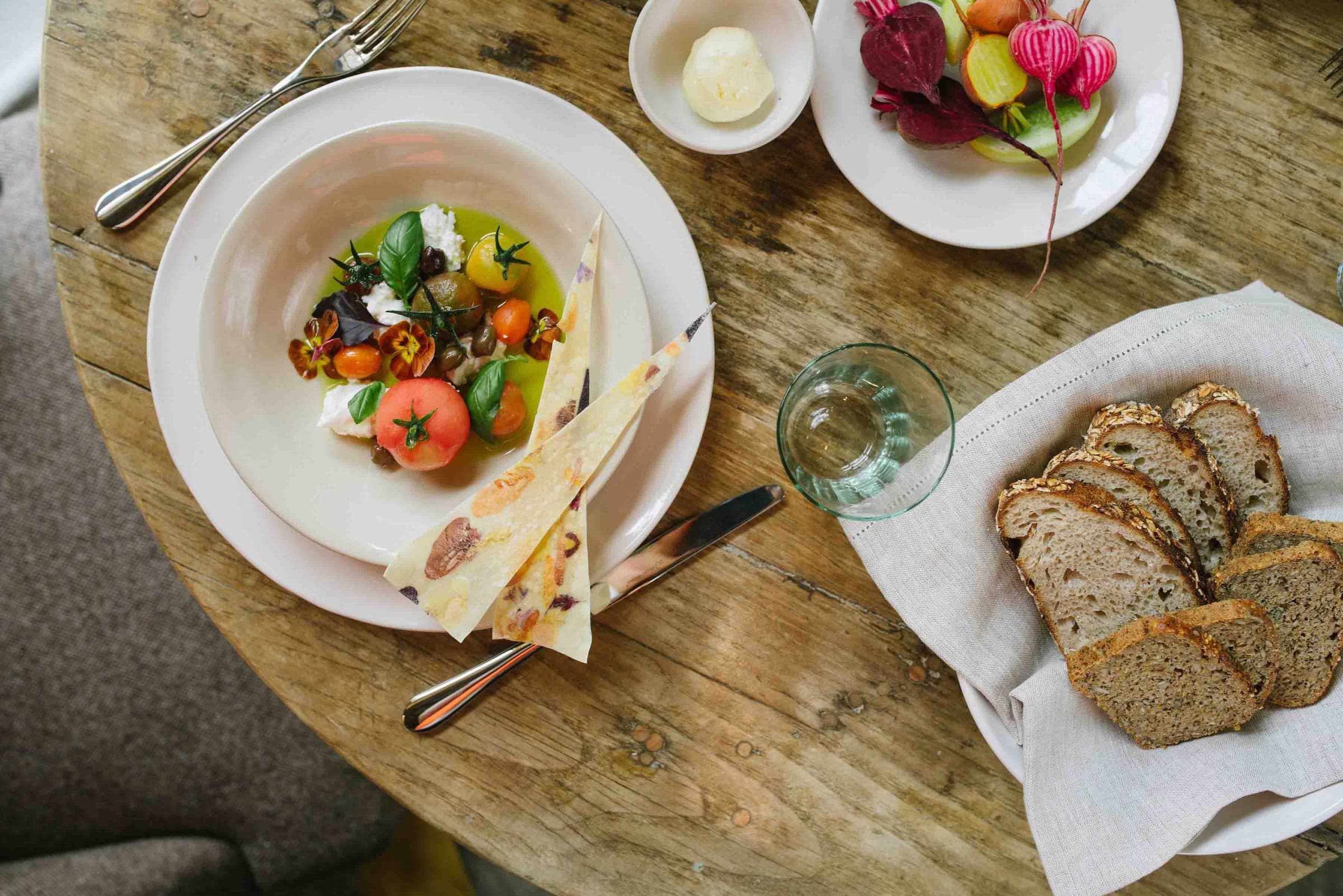 A breakfast laid at Hearth, the property's fireside dining room, a generous table with bread, fruit and warm light.