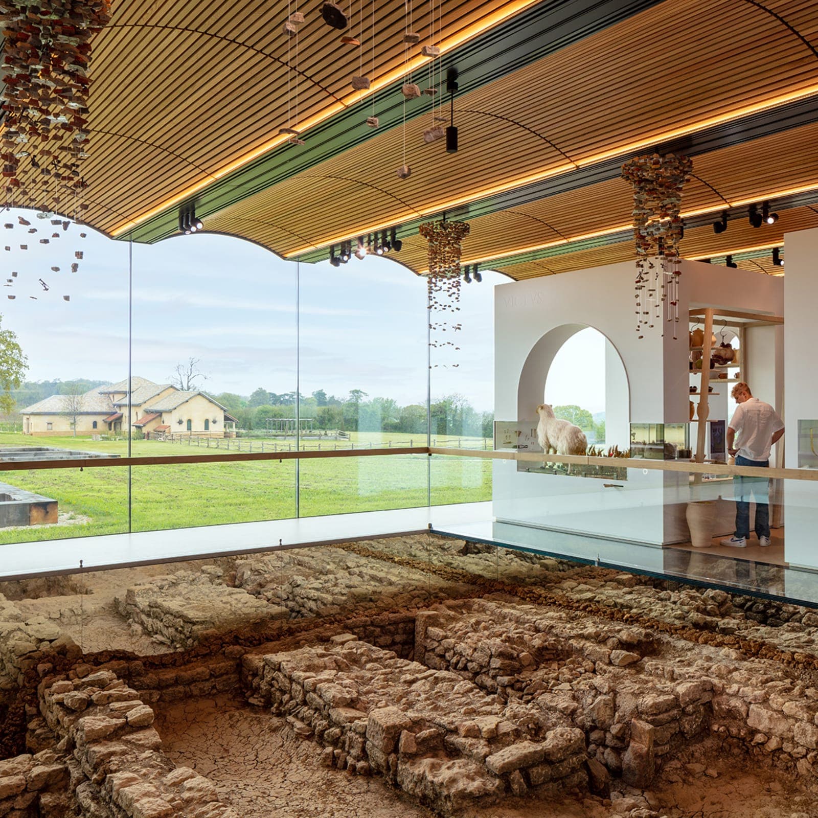 The Roman Villa café — a curved glass dining room overlooking the excavated foundations of a Roman villa, hung with reed-bound chandeliers.